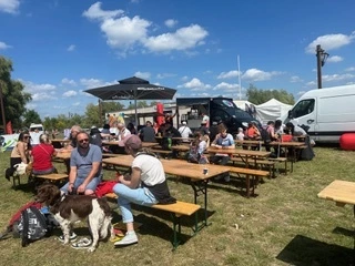 Table et des bancs en extérieur sous un ciel bleu avec au fond le foodtruck